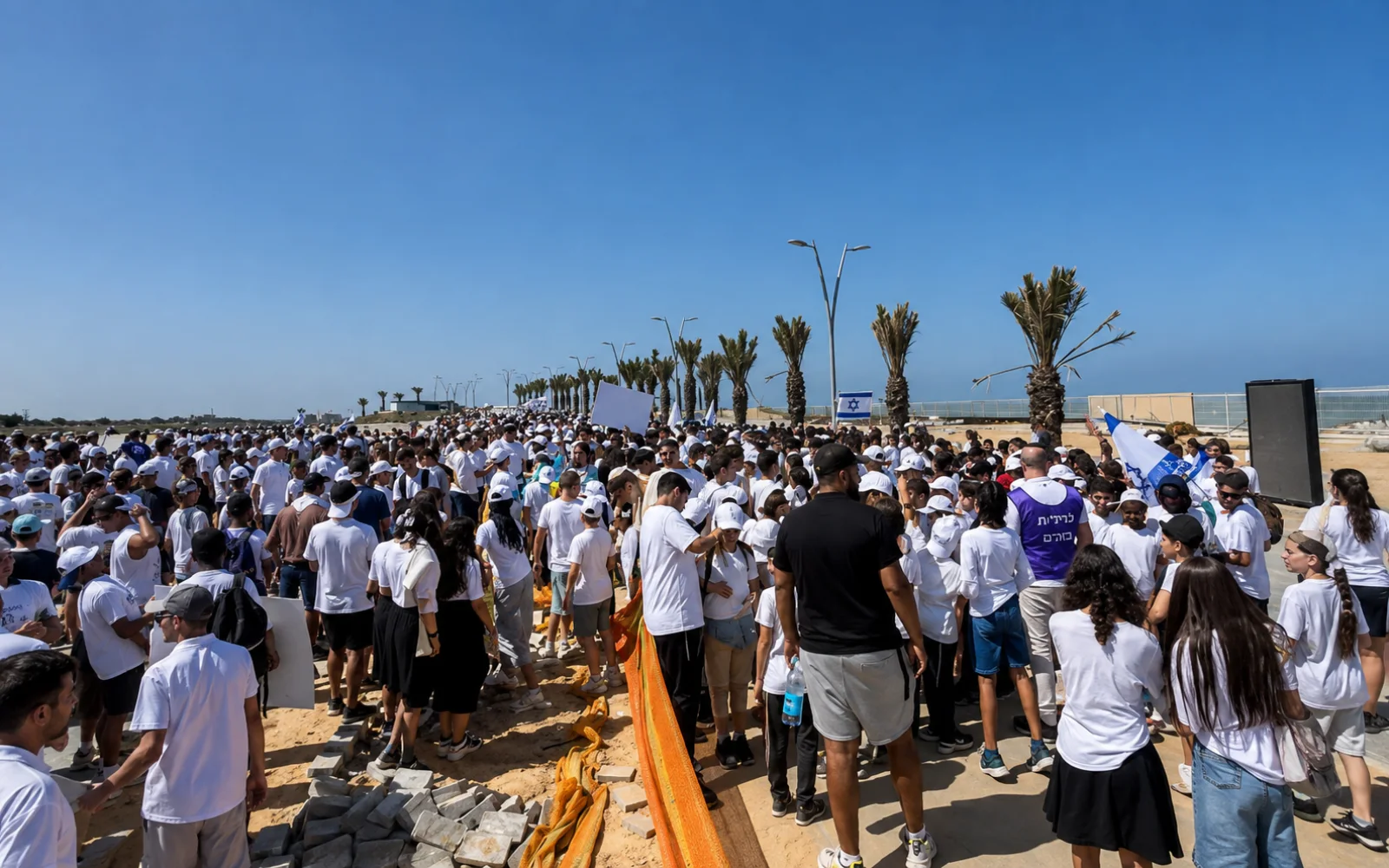 קהל לבוש לבן צועד בטיילת לצד דגלי ישראל