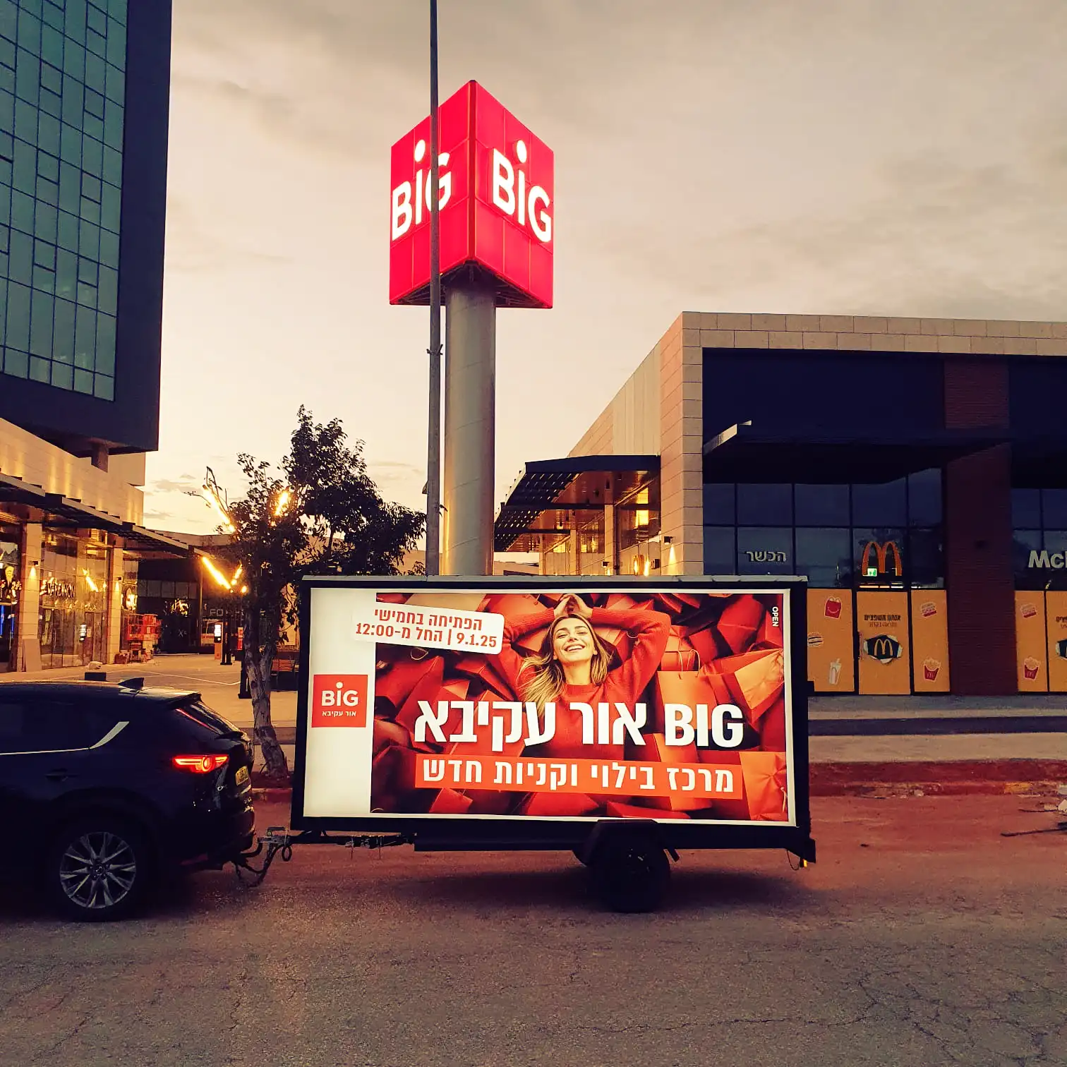מסך נייד מציג מודעת BIG אור עקיבא סמוך לכניסה למתחם