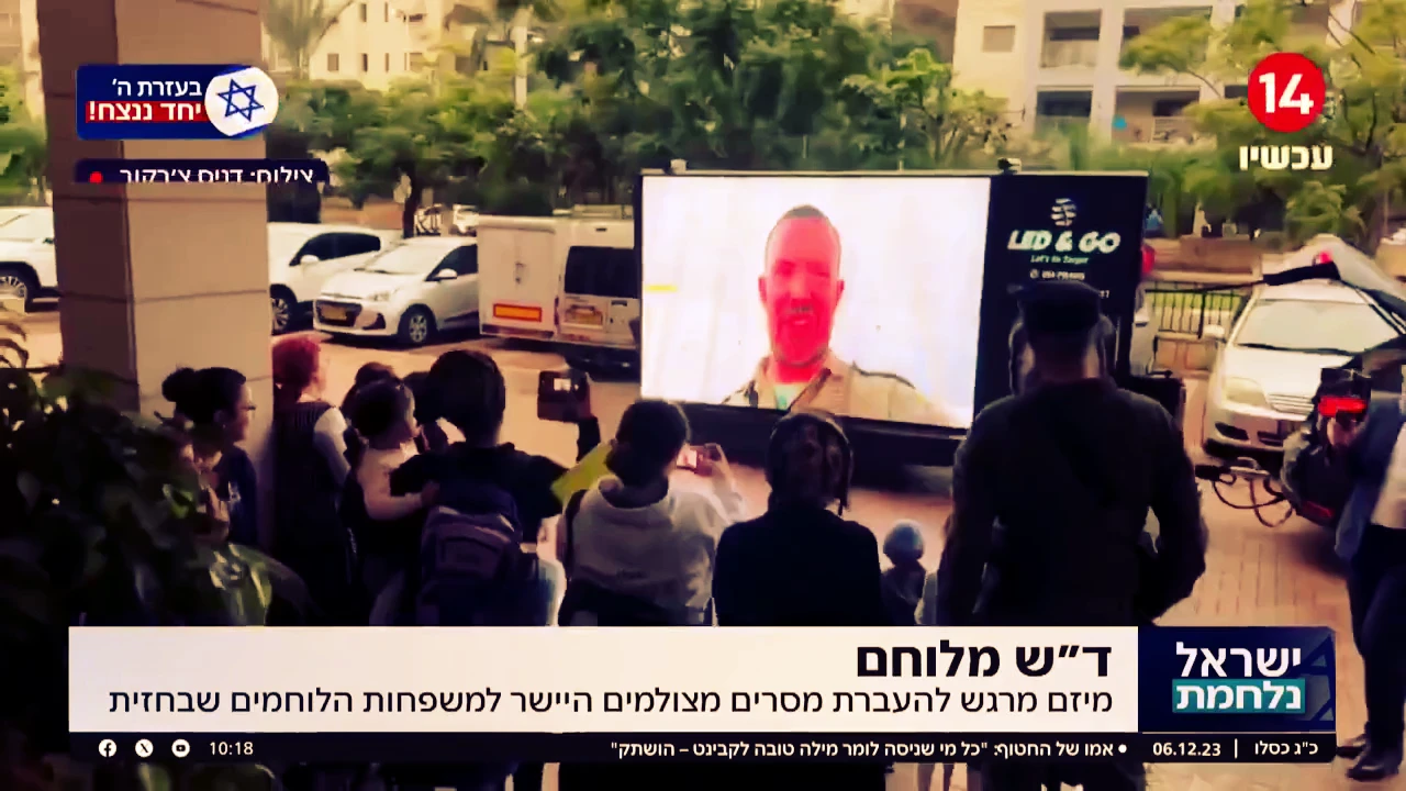 משפחות צופות באדם במדים המוקרן על מסך LED נייד
