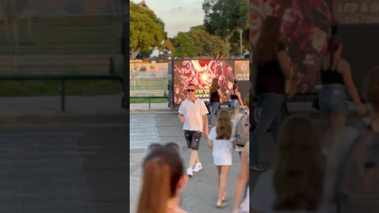 קהל הולך לצד מסך LED נייד בכניסה למתחם פתוח