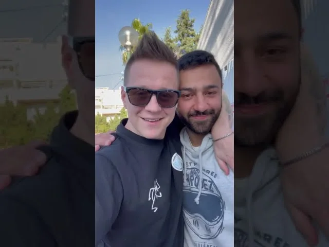 שני גברים מצטלמים יחד בחוץ בתמונת הפתיחה של הסרטון